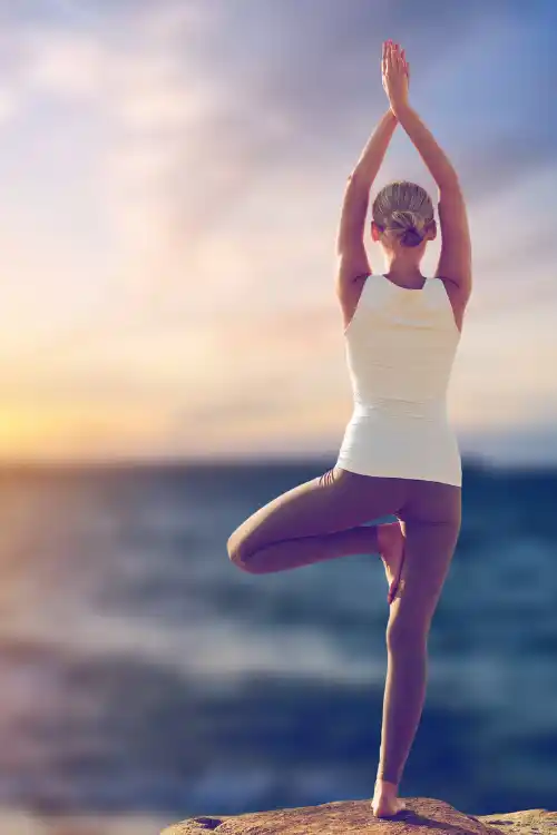 Femme pratiquant une pose de yoga au lever du soleil