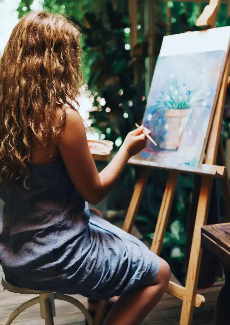 Fille aux cheveux longs peignant une plante sur une toile